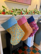 Three patterned stockings hanging on a fireplace mantle with holly decorations.