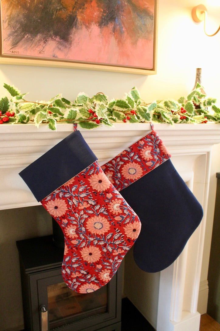 Two Christmas stockings hanging on a fireplace mantle with festive decorations.