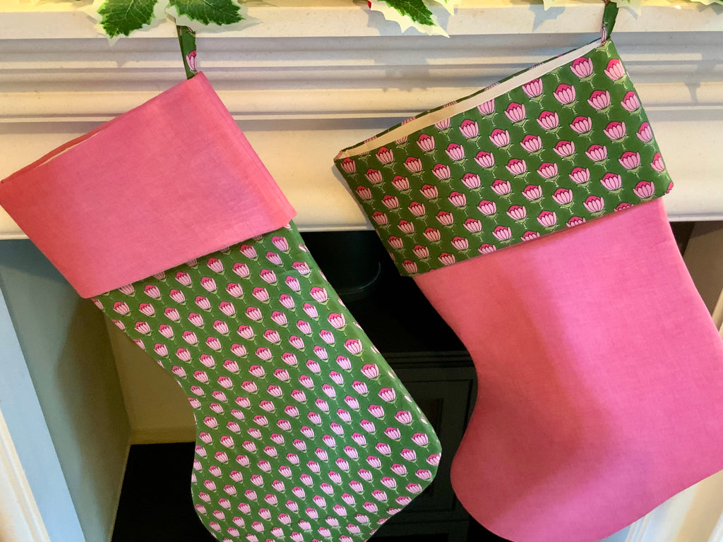 Two hanging christmas stockings with green floral blockprint pattern 