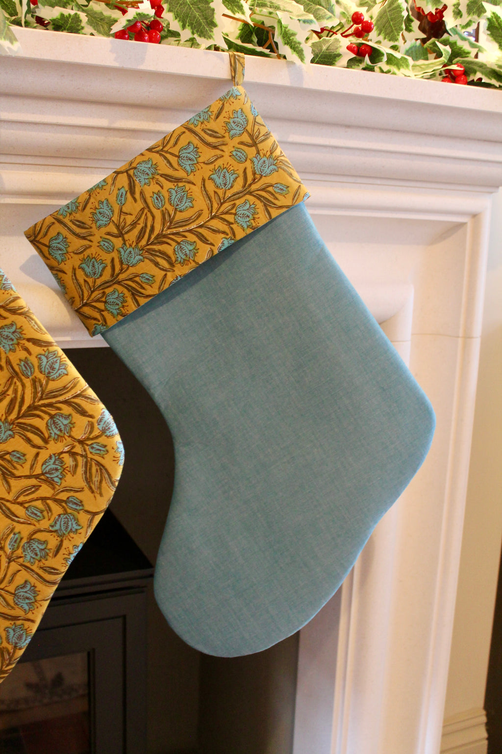 Blue and yellow Christmas stockings hanging on a fireplace mantle.