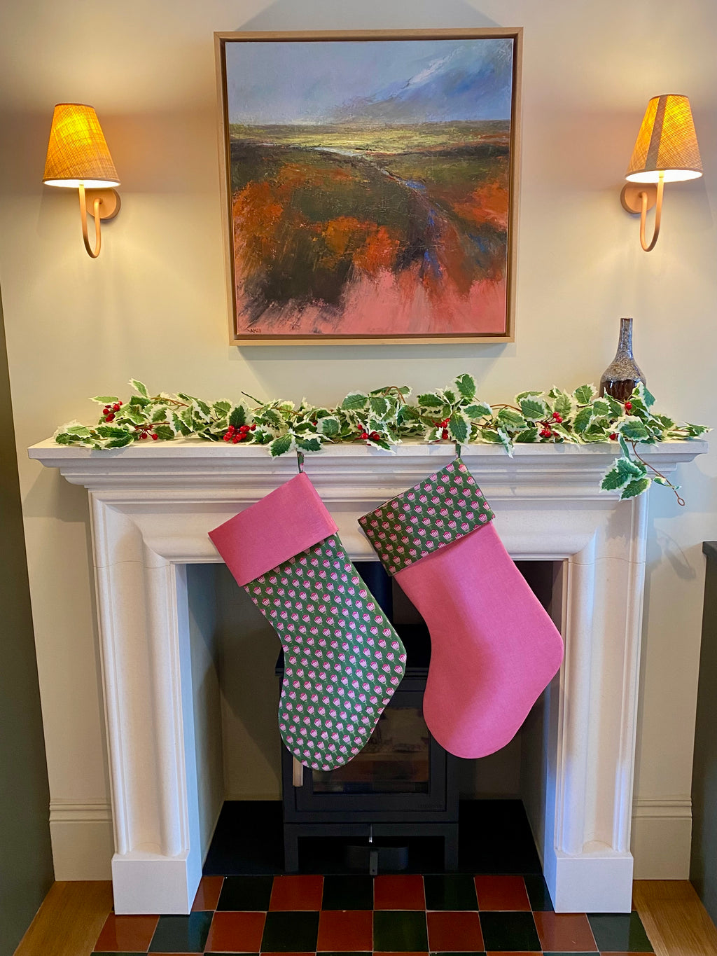 Two indian blockprint stockings hanging on a fireplace mantle decorated with holly