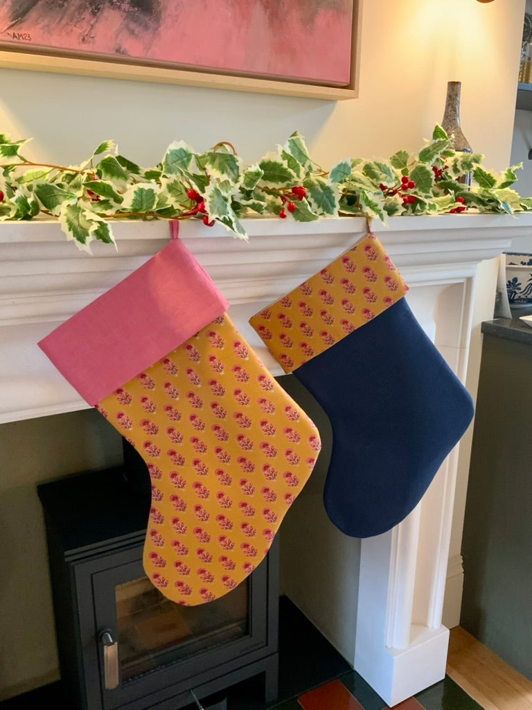 two colorful stockings hanging on a fireplace mantle with holly decorations.