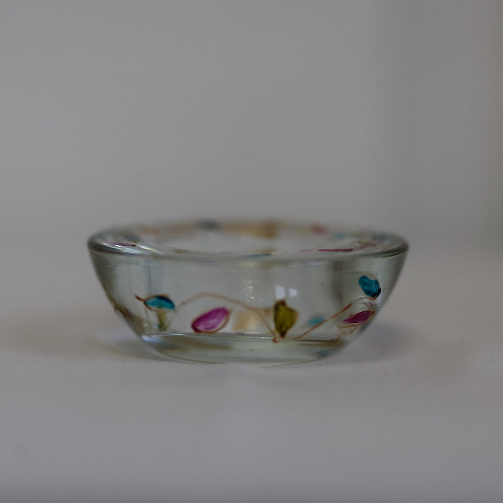 Small glass candleholder with colorful designs on a plain background