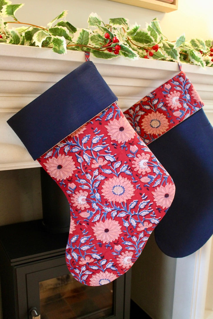 Floral-patterned Christmas stockings hanging on a fireplace mantle.
