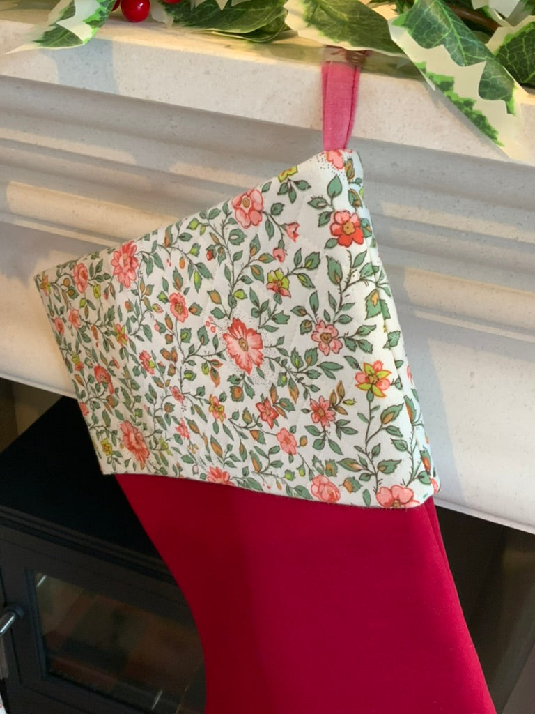 Floral-patterned fabric hanging from a red stocking on a white surface.