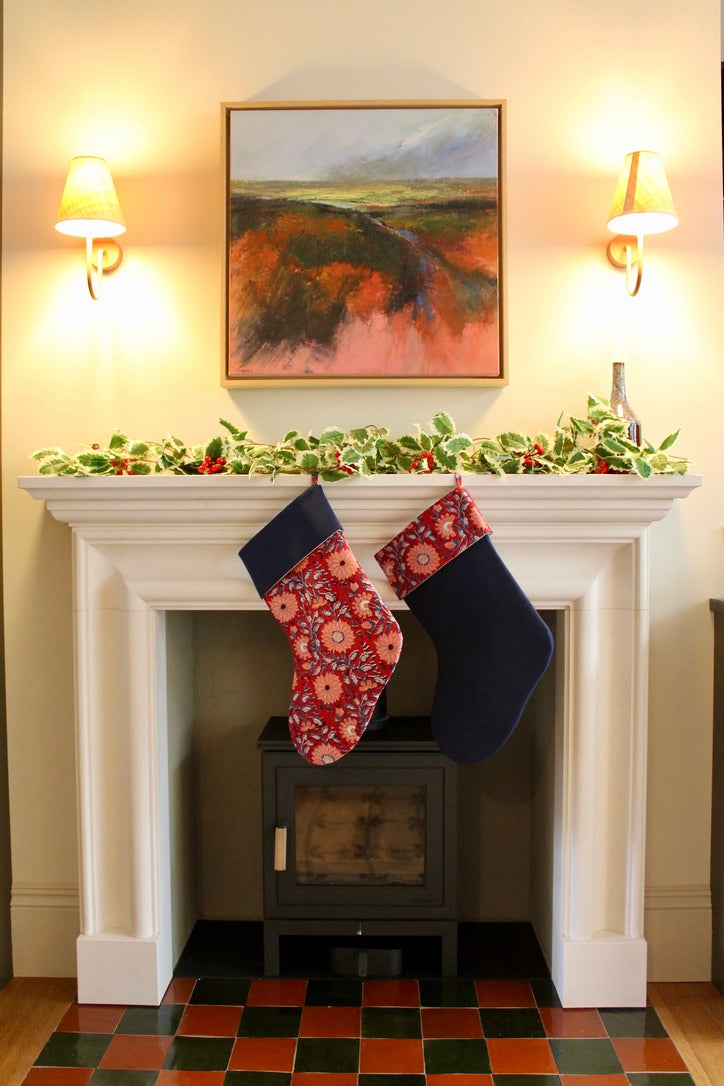 Two Christmas stockings hanging above a fireplace with festive decorations.