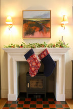 Two Christmas stockings hanging above a fireplace with festive decorations.