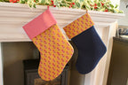 Two Christmas stockings hanging on a fireplace mantle with festive decorations.
