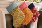 Three blockprint patterned stockings hanging on a fireplace mantle.