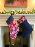 Two Christmas stockings hanging on a fireplace mantle with festive decorations.