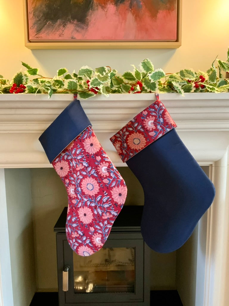 Two Christmas stockings hanging on a fireplace mantle with festive decorations.