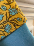 Close-up of a christmas stocking with yellow fabric with blue floral patterns on a blue background