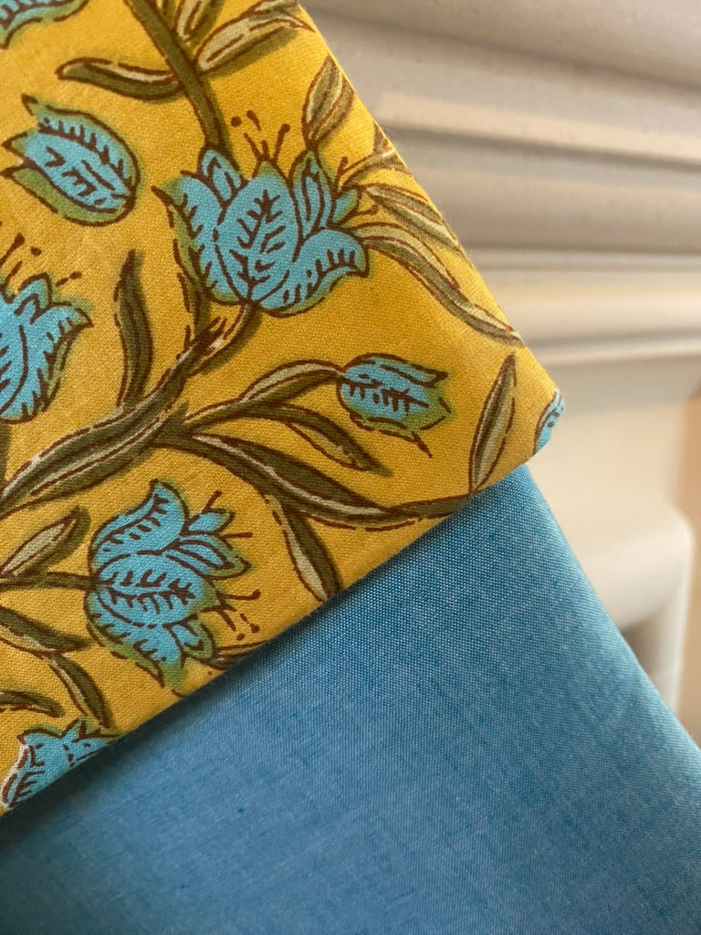 Close-up of a christmas stocking with yellow fabric with blue floral patterns on a blue background