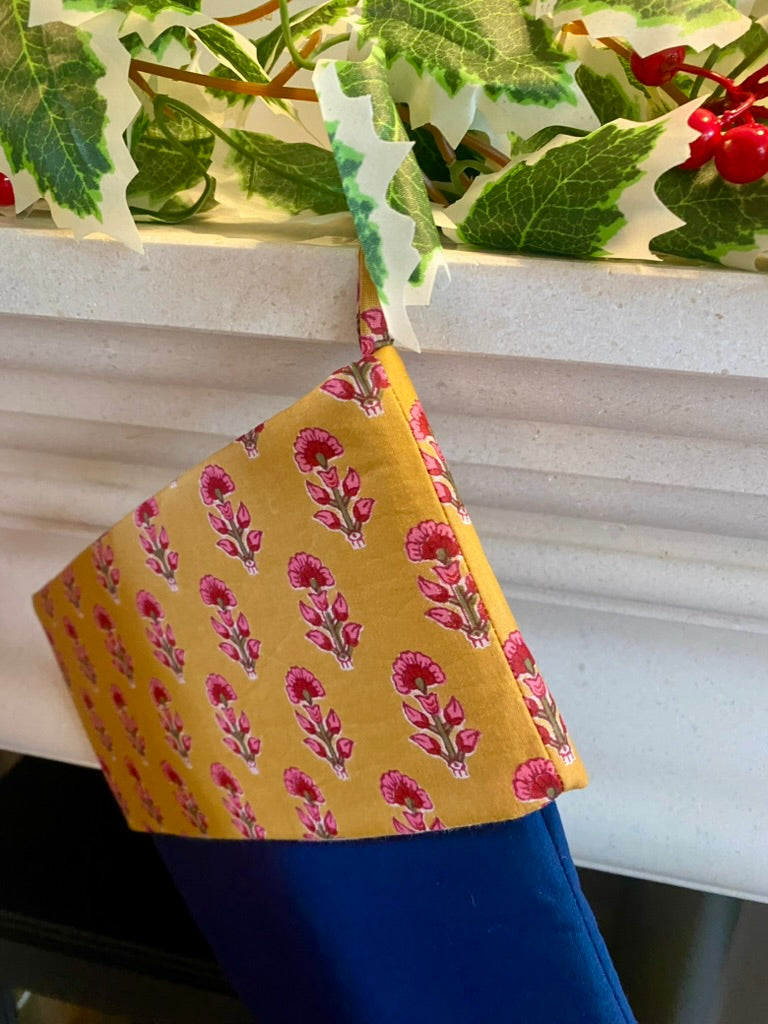 indian blockprint chritsmas stocking with navy and gold pattern hanging on fireplace