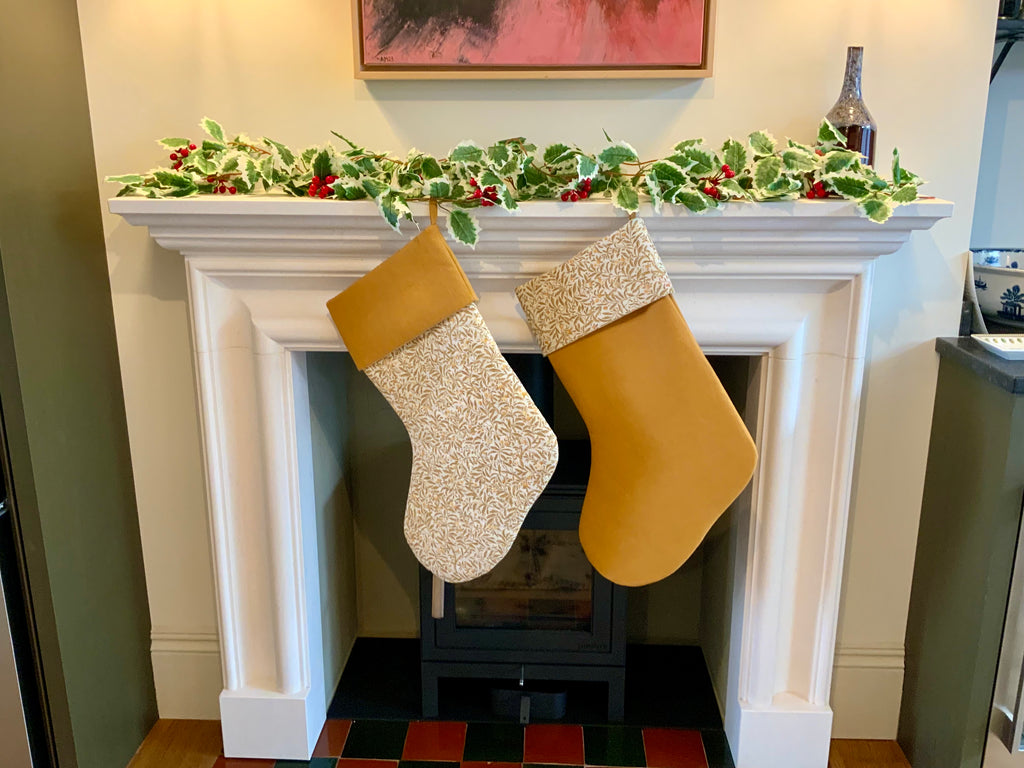 Two Christmas stockings hanging on a fireplace mantle with a garland above.