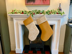 Two Christmas stockings hanging on a fireplace mantle with a garland above.