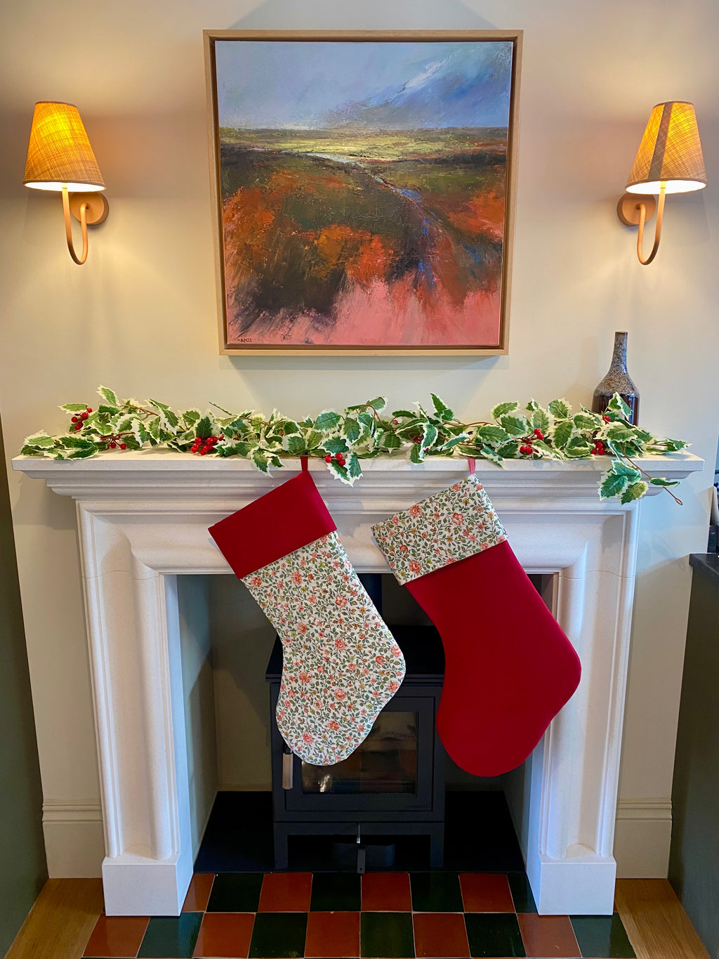 Two Christmas stockings hanging by a fireplace with festive decorations.