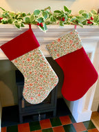 Two Christmas stockings hanging by a fireplace with a decorative garland above.