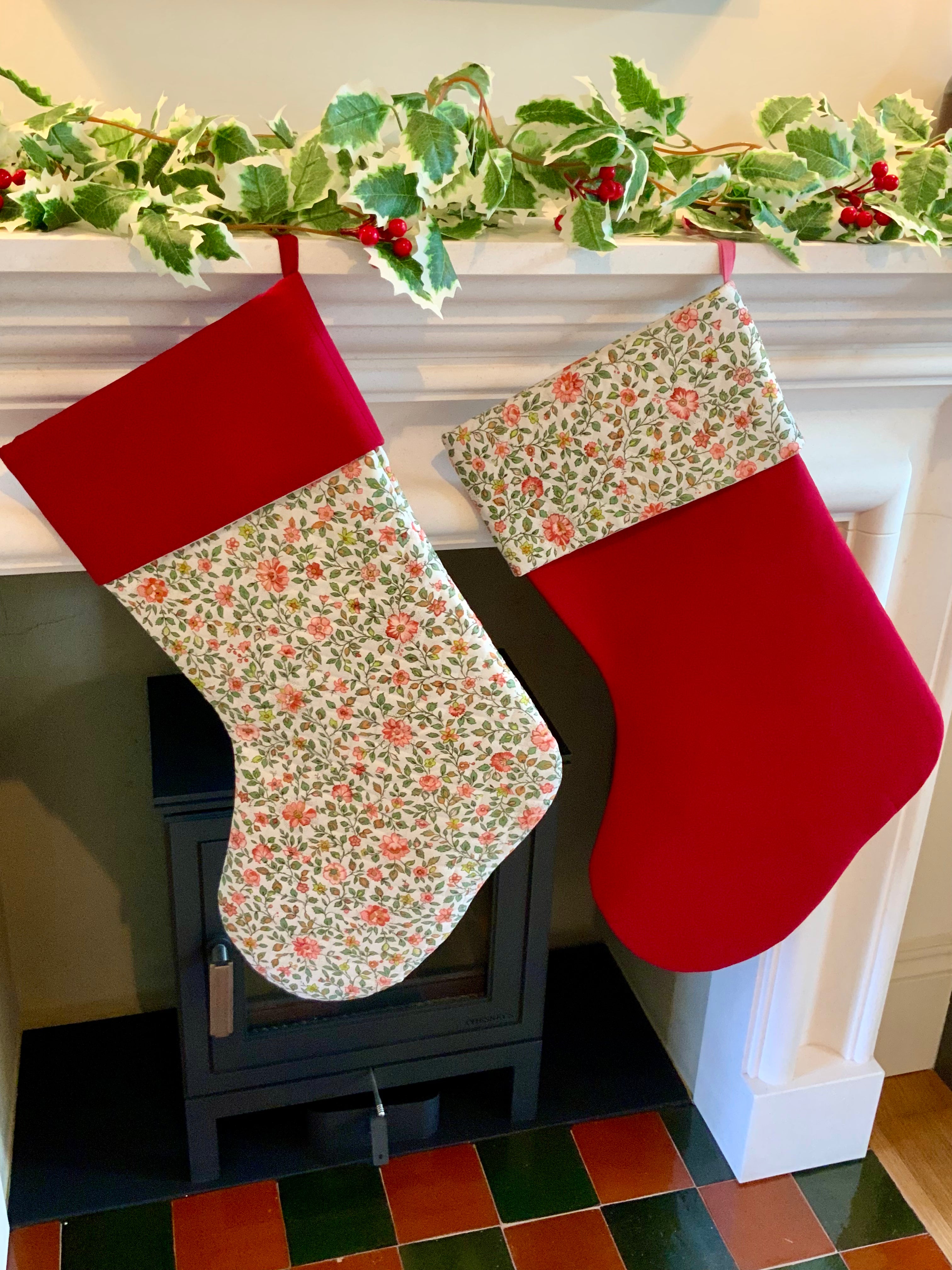 Two Christmas stockings hanging by a fireplace with a decorative garland above.
