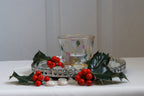 Decorative tealight holder with holly leaves and berries on a white surface