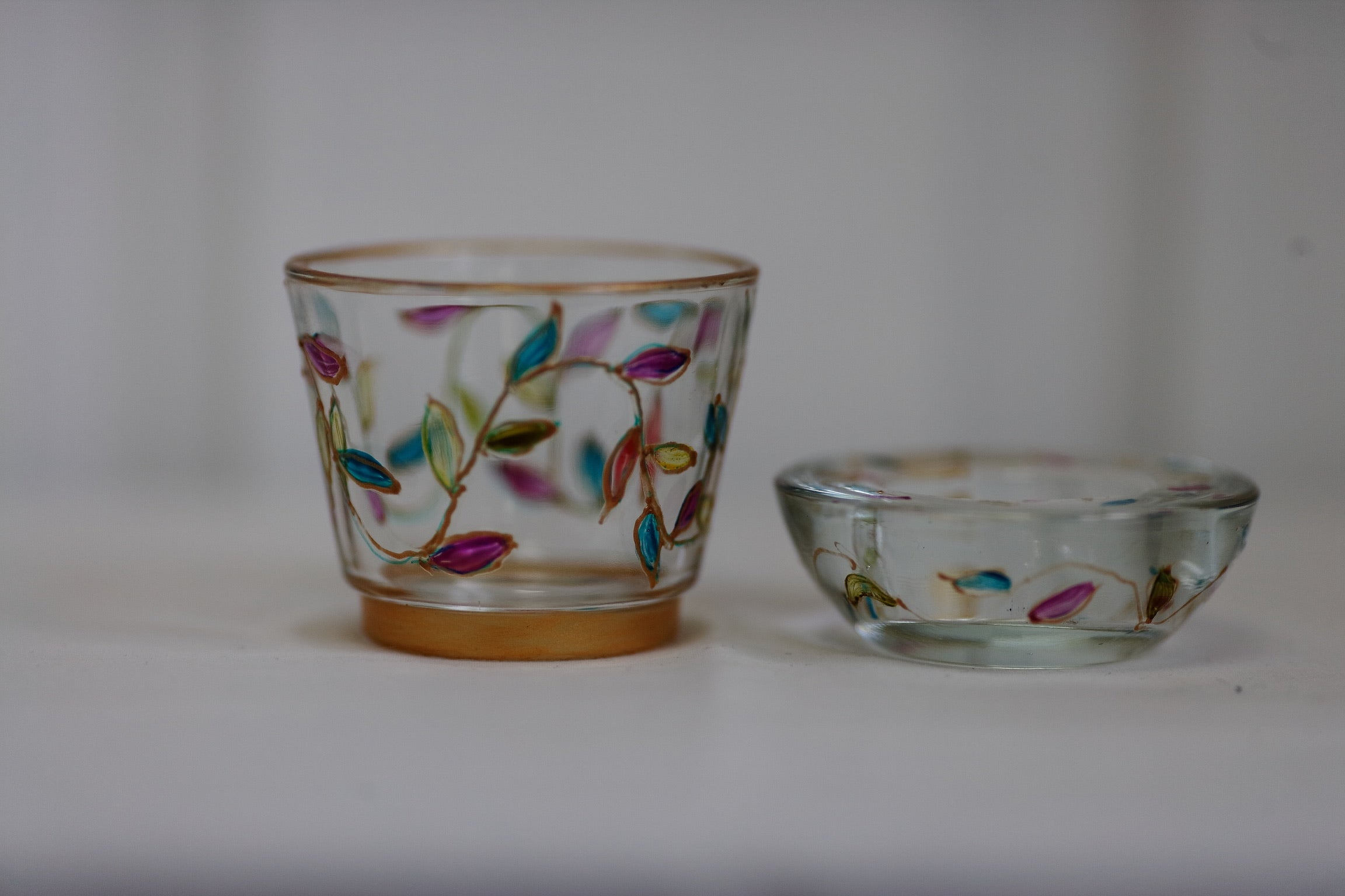 Two glass tealights with floral designs on a white background