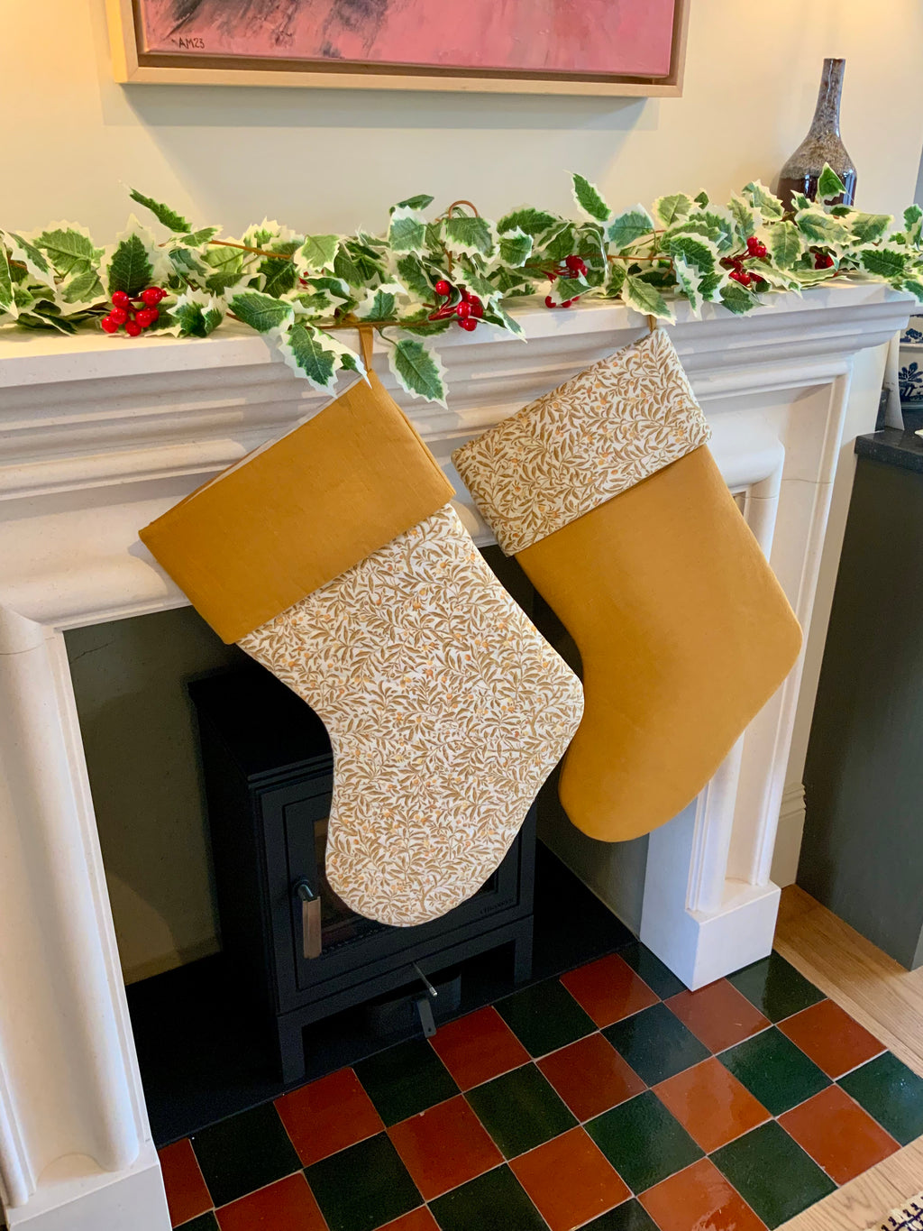 Two Christmas stockings hanging on a fireplace mantel with festive decorations.